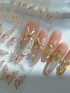 Close-up of gold-stamped butterfly nail stickers with rhinestones and pearl charms