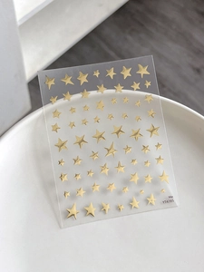 Detail of metallic gold star nail stickers YT4785 on white marble background