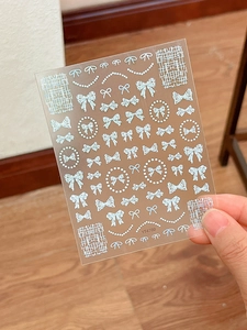 Detail of embossed silver bow and pearl necklace nail art stickers with PET backing