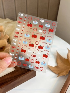 Detail of 3D embossed nail art stickers with red apple and cute bow tie patterns