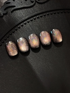 Detailed view of dark cat-eye false nails with rainbow laser firework patterns