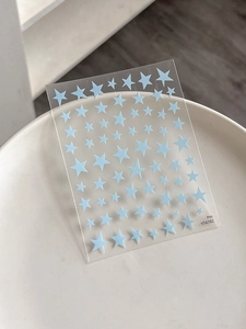 Detailed close-up of light blue star nail art stickers on a transparent sheet