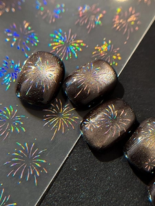 Macro view of laser holographic firework nail stickers with iridescent starburst patterns