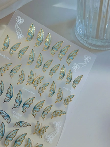 Close-up of Butterfly Dream nail stickers with gold foil outlines and blue watercolor wings