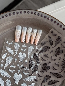 Detail view of black and white wing nail stickers with crown and star motifs on nails