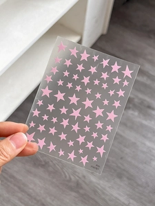 Close-up of pink star nail art stickers in various sizes on a transparent sheet