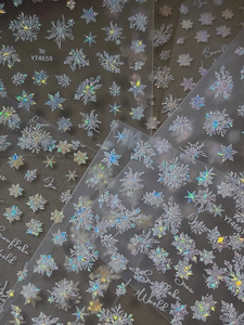 Macro detail of holographic snowflake nail art stickers with laser glitter finish and text