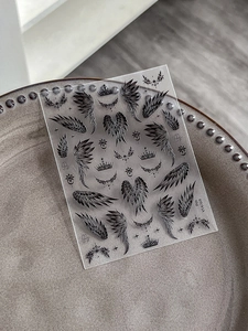 Detail of wing and crown nail art stickers with star elements on transparent backing