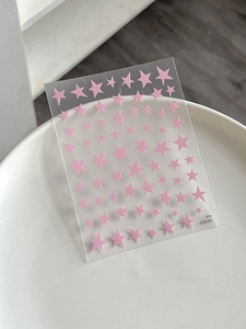 Pink pentagram star nail art stickers in various sizes on a white ceramic plate