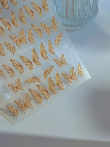 Close-up of Butterfly Dream nail stickers with gold outlines and peach pink details