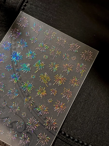 Macro shot of holographic laser firework nail stickers with vibrant rainbow reflection