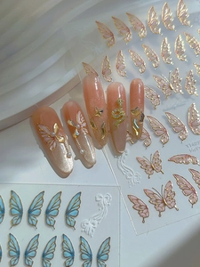 Close-up of 3D gold butterfly nail art stickers with metallic snake and rhinestone detail