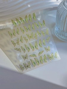 Detailed view of green butterfly nail art stickers with gold foil lines and delicate patterns