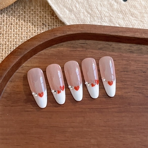French tip press-on nails with red hearts and pearl rhinestones on wood display