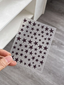 Detail of diverse black five-pointed star nail art stickers in various sizes