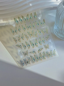 Detailed close-up of blue butterfly nail stickers with gold stamping on white waves