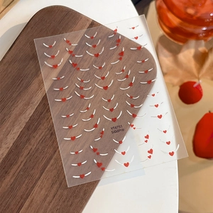 French silver heart nail art stickers with red patterns on rustic wood background