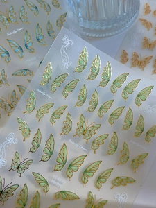 Macro detail of bronzing butterfly nail stickers showing liquid lines and textures
