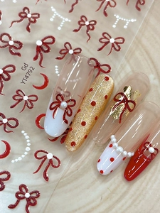 Vue détaillée des autocollants d'ongles avec nœuds rouges sur faux ongles manucurés