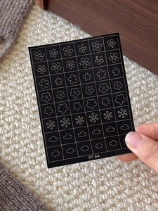 Detail view of black and gold nail art stickers with flower and snowflake patterns on YT84 sheet
