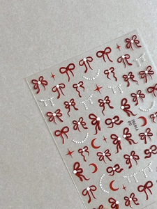 Gros plan sur les autocollants à ongles nœud rouge et étoile lune en relief