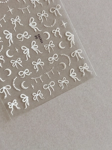 Vue détaillée de l'embossage 3D de nœuds blancs et d'autocollants nail art lune étoilée