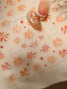 Detail of laser holographic firework nail stickers with gold and red patterns