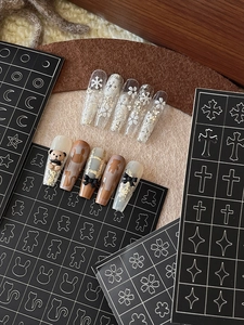 Detailed close-up of brown press-on nails with bear, ribbon, and animal silhouette designs