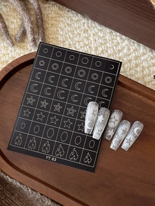Close-up of star and moon nail stickers on silver glitter nails over a wooden tray