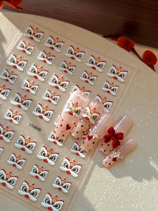 Close-up of embossed dancing lion nail stickers with red bows on pink manicure