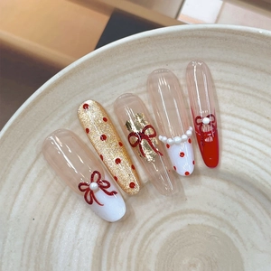 Ongles à presser rouge et blanc avec nœuds 3D et perles sur une plaque texturée blanche