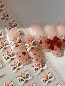 Detail view of 3D embossed lion dance nail art stickers with red velvet bows and pearls