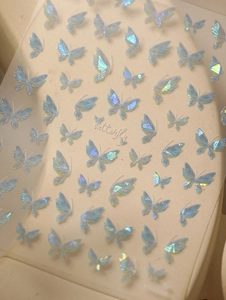 Detail of aurora butterfly nail stickers with holographic shell effect on light background
