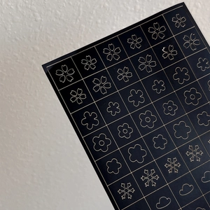 Adhesive gold metallic nail stickers with snowflake flower and star designs on black base