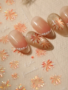 Macro shot of 3D firework nail art stickers with pearls and warm golden glitter effects