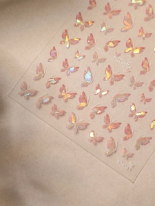 Close-up of holographic aurora butterfly nail stickers with pink and gold gradient accents