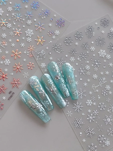 Macro detail of holographic silver snowflake nail stickers on blue gradient manicure