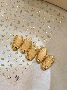Detail of 3D gold floral nail stickers with green leaves on cat-eye base color