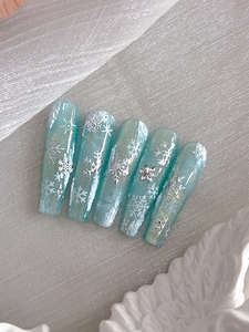 Macro view of blue gradient press-on nails with silver snowflake and 3D snow textures