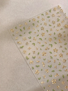 Detailed view of bronzed five-petal gold flowers and green leaf nail art stickers