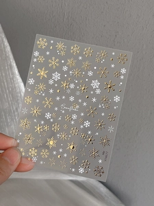 Detail of gold and white snowflake nail stickers with shiny bronzing effect YT4677