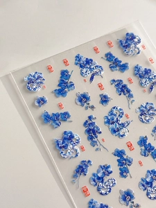 Detailed macro view of blue porcelain orchid nail stickers with red lucky seal motifs