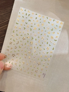 Macro view of self-adhesive nail stickers with gold foil flowers and green leaf patterns