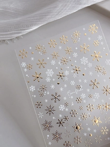 Detailed view of gold and white snowflake nail stickers with embossed metallic textures