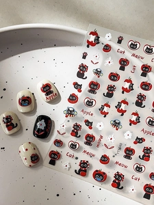 Detail of cute black cat and red apple embossed nail stickers with finished manicures