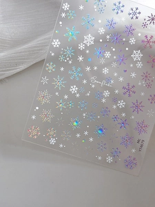 Detailed macro view of laser snowflake nail art stickers with holographic winter patterns