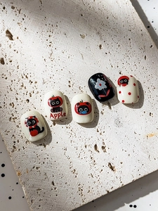 Close-up of cute black cat and red apple embossed nail stickers on stone base