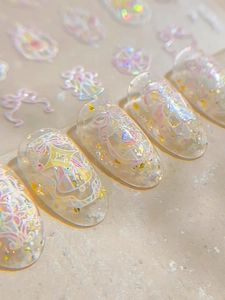 Macro shot of 3D embossed holographic nail stickers with bows and stars on white crystals