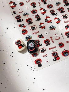 Detail of red apple and black cat nail art stickers with embossed 3D texture effect