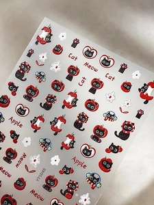 Detail of cute embossed nail stickers featuring black cats, red apples, and floral patterns